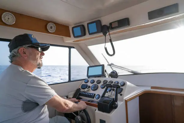 Active senior sailing motorboat happy retirement as sailor captain in indoor yacht