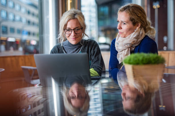 Two females using laptop in coffee bar stock photo