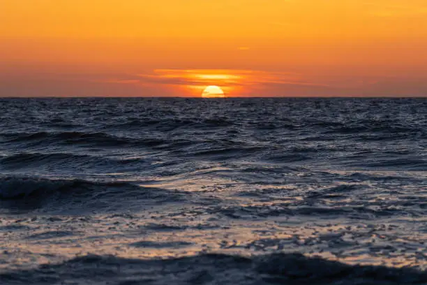 Sun setting under the horizon by the North Sea, Belgium.