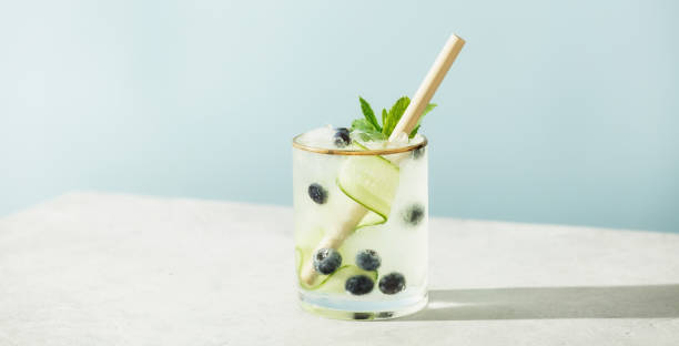 istock Trendy summer drinks with cucumber, mint and blueberry on blue sky background 1404077047