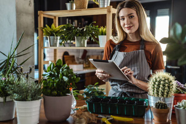 istock Smiling young woman posing with digital tablet surrounded by houseplants 1404077789