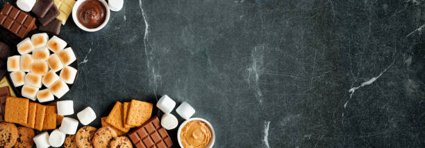 istock Smores buffet corner border, overhead view over a dark stone background 1404078911