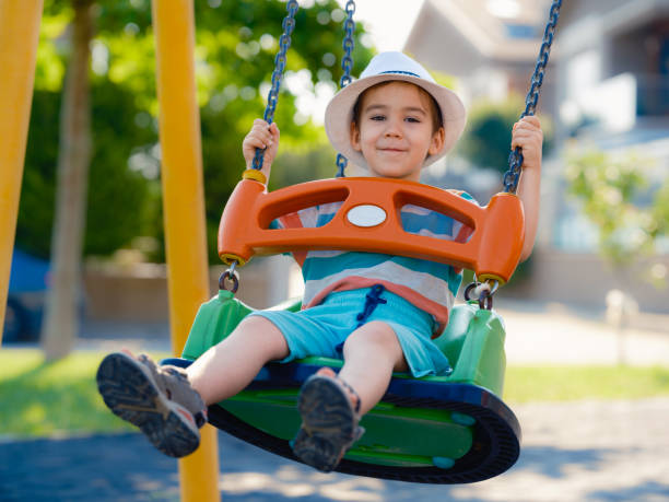 istock Little boy is swinging at play ground when sun is setting 1404079579