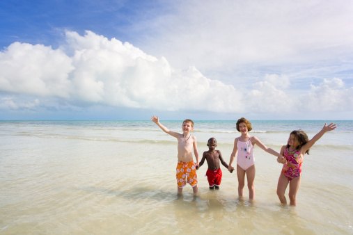 Four small children of diverse races playing on a white sands beach. Bahia Honda, Florida Keys.