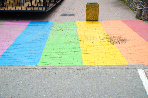 LGBTQ pride rainbow flag painted on sidewalk during summer day