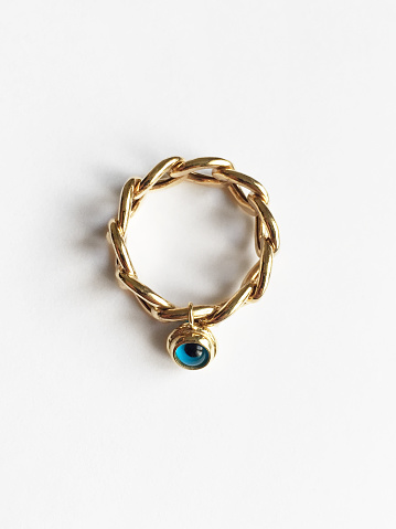 Gold ring with evil eye bead on the white background