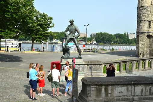 Antwerp city, Province Antwerp , Belgium - June 18, 2022: Lange Wapper standing with open legs is a giant of Antwerp folklore. Tourists in front of Lange Wapper statue and Het Steen fortress