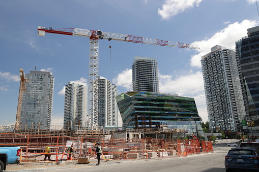 Surrey, Canada - June 17, 2022: Construction of new residential buildings in progress along King George Boulevard and 98A Avenue. Background shows the modern downtown district around the SkyTrain King George Station. Spring morning.