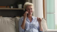 istock Blond aged woman lead conversation on smartphone sit on sofa 1404089190