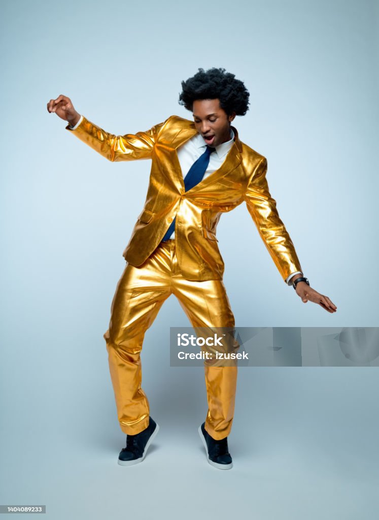 Man enjoying and dancing against blue background Businessman in golden suit enjoying while dancing against blue background Men Stock Photo