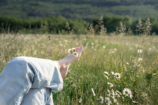 Young girl relaxing lies on a spring flowering meadow. Travel vacation and healthy lifestyle, enjoying nature. Freedom and healthy concept