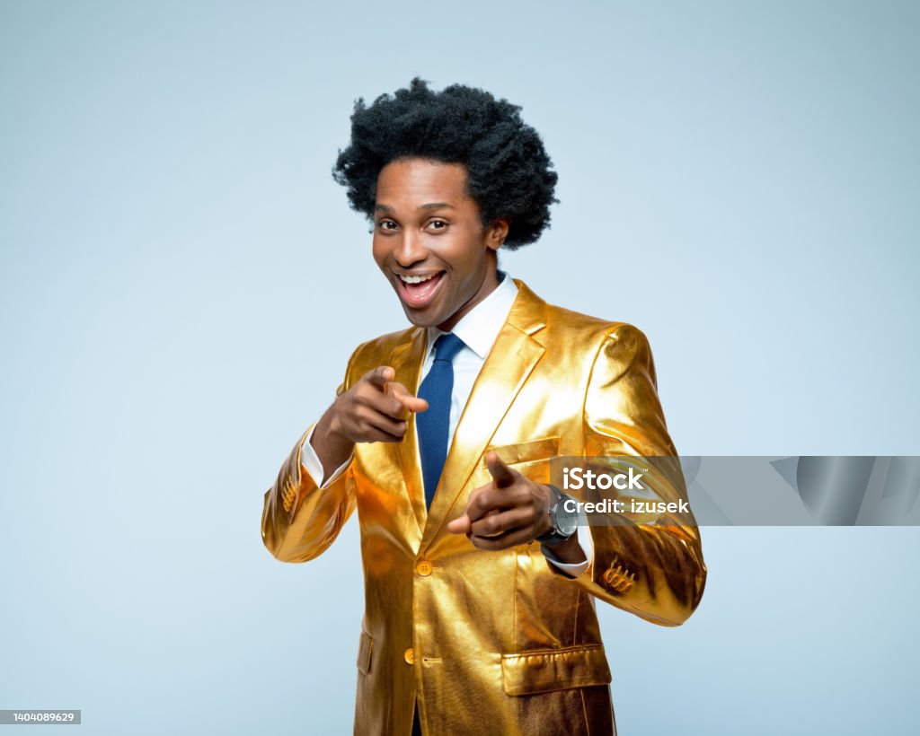 Happy man in golden blazer pointing Portrait of happy businessman in golden blazer pointing while standing against blue background Men Stock Photo