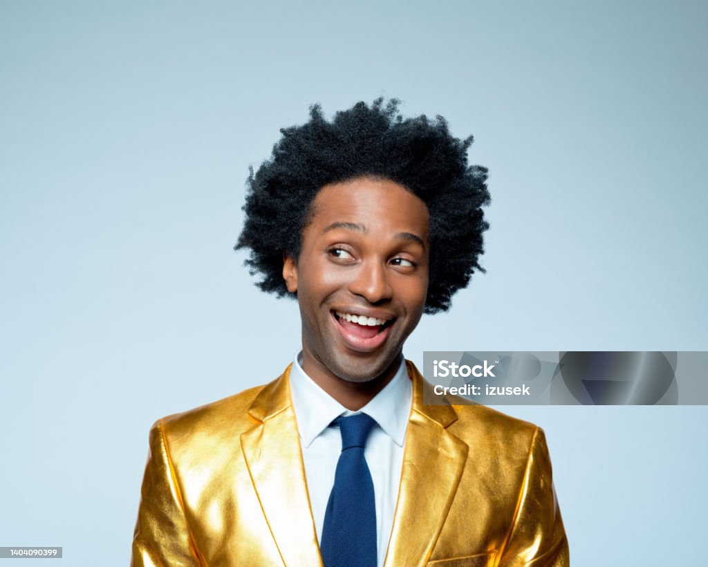 Happy businessman looking sideways glance Happy businessman in golden blazer looking sideways glance against blue background Gold Colored Stock Photo