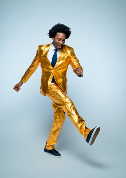 Portrait of charming mid adult man in a suit, standing against dark green background and playing with a disco ball.