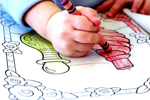 Little child coloring in coloring book with crayons