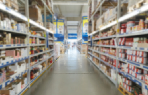 Blurred supermarket aisle with colorful shelves of merchandise. Perspective view of abstract supermarket aisle with copy space in center, can use as background or retail concept.