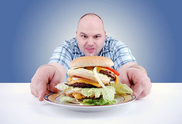 A man with a big greasy burger on a plate stock photo