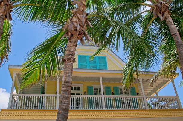 Second story balcony and railing of typical Key West Florida architecture with hurricane shutters at the ready Second story balcony and railing of typical Key West Florida architecture with hurricane shutters at the ready from June 2010. Brightly painted Florida Keys architecture depicting protection from sun and hurricanes but allow sea breeze air flow when conditions are favorable. Tropical Queen palms in the foreground. syagrus stock pictures, royalty-free photos & images