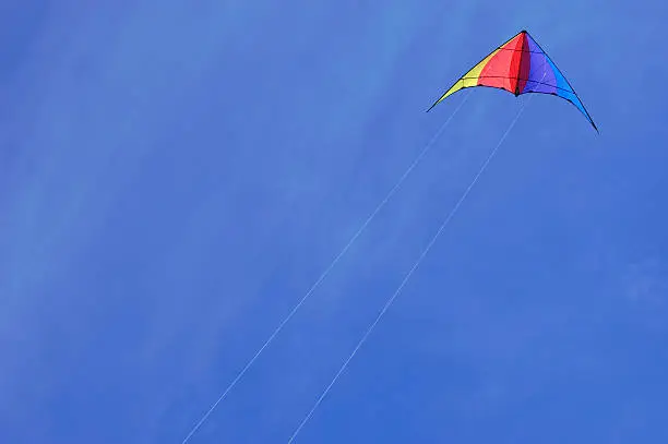 Colorful stunt kite being flown against a deep blue sky