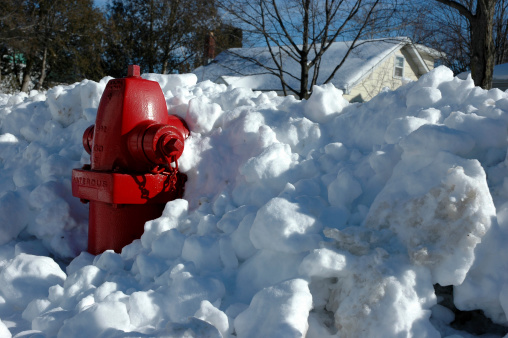 Bright red fire hydrant trapped in a snow bank. Horizontal composition.
