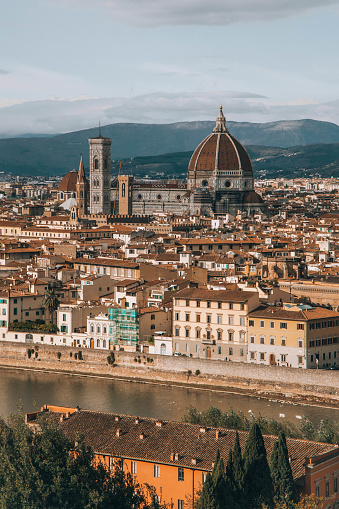 View from hill overlooking city of Florence Italy with the Santa Maria feel Fiore Cathedral as a central focus. View of river at bottom and mountains in the background