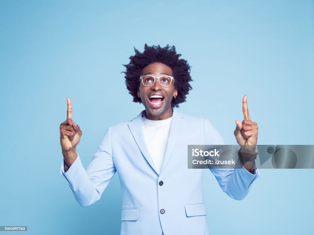 Man pointing with index fingers against blue background Cheerful businessman in blue blazer pointing with index fingers against colored background Business Person Stock Photo