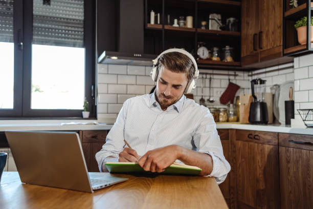 istock Young man sitting at the table in the kitchen and working 1404098405