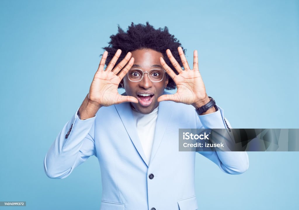 Businessman making finger frame Surprised businessman making finger frame against blue background 30-34 Years Stock Photo