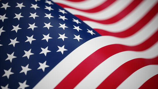 Beautiful American flag waving in the wind, with vibrant red white and blue colors against blue sky, with copy space.