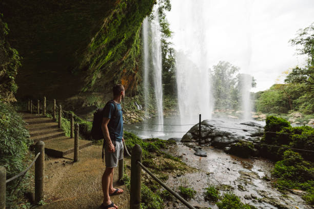 Caucasian man enjoying the view of Misol-ha waterfall in the middle of the jungle in Mexico.