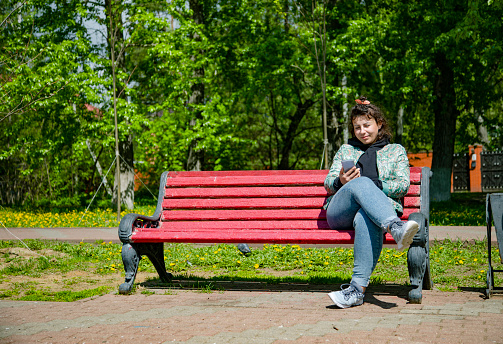 Young woman sitting on a bench among dandelions
