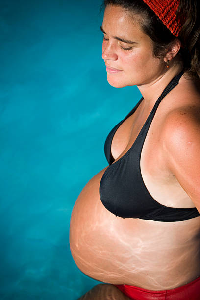 Mulher grávida em uma piscina (Perfil - fotografia de stock