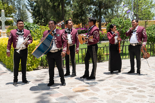 Tlacolula de Matamoros, Oaxaca, Mexico- May 23, 2022: Members of mariachi waiting outside of Parroquia Santa Maria de la Asuncion at a sunny day in Tlacolula, Oaxaca, Mexico