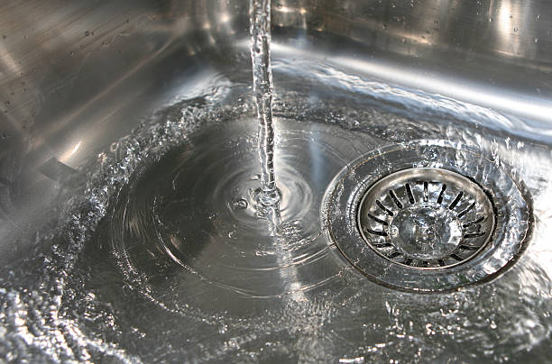 istock Water pouring into a silver sink and draining down the drain 140411200