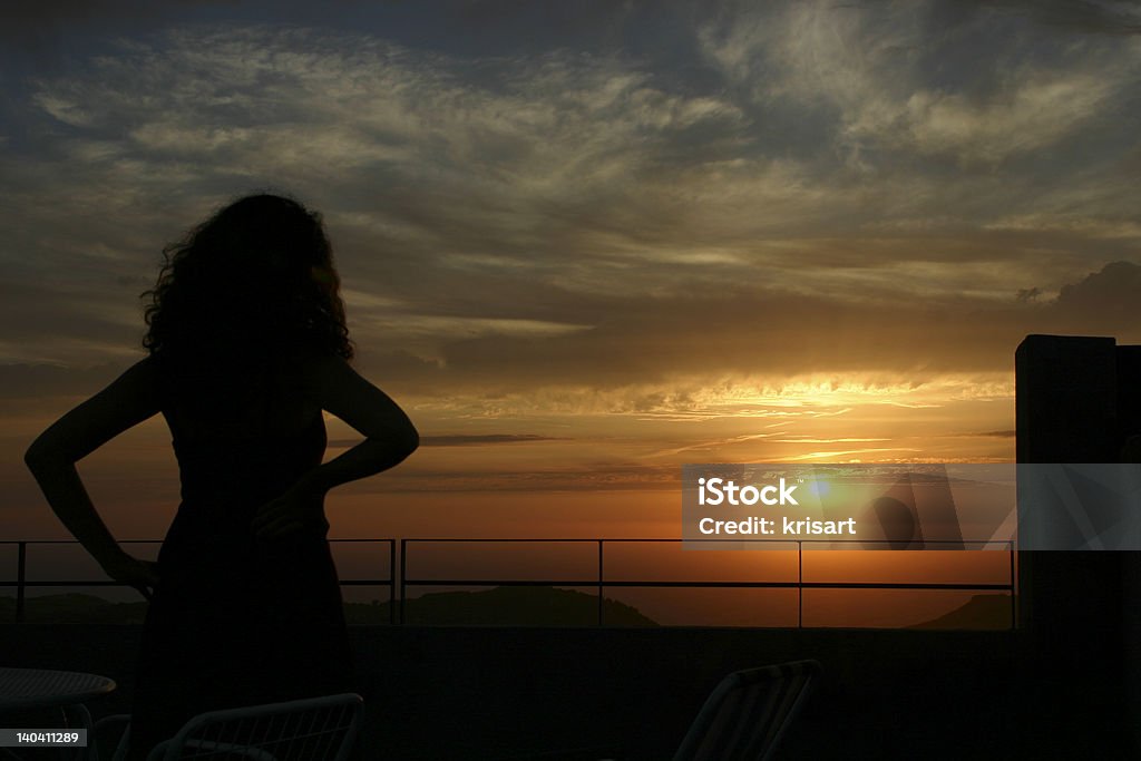 sardinia sunset a woman looks the horizon, the sun is falling in the sea. Great Sunset and silhouette. Adult Stock Photo