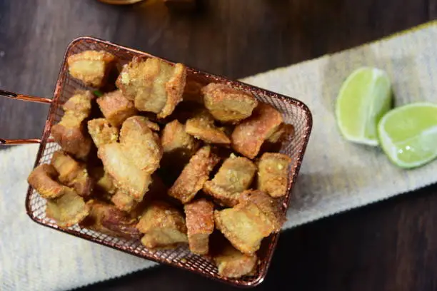 Photo of crackling, fried or roasted pork skin with lemon and cachaça typical Brazilian food