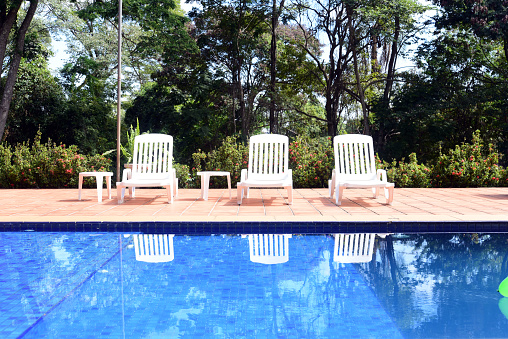 pool with white chairs and natural garden in the background