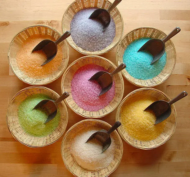An arrangement of different coloured Dead Sea bath salts in bowls.