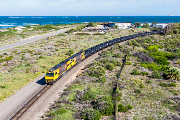 luftaufnahme leerer eisenerzzug mit sanddünen und küste - land vehicle rail freight locomotive australia stock-fotos und bilder