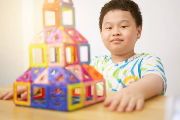 asia boy make house from plastic block toy in construct concept