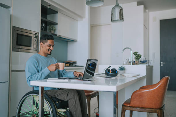 istock Asian Indian man with disability working at home typing using laptop smiling 1404119788