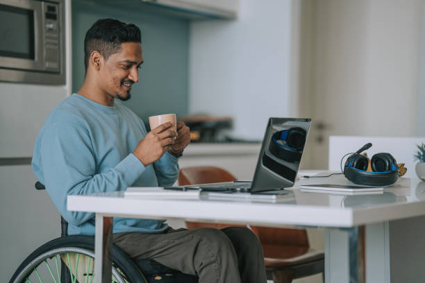 istock Asian Indian man with disability working at home typing using laptop smiling 1404119789