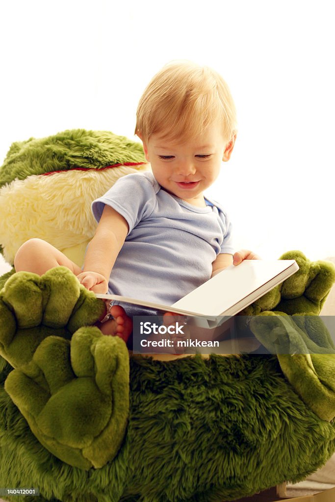 Sonriente bebé leyendo un libro en rana silla - Foto de stock de Rana libre de derechos