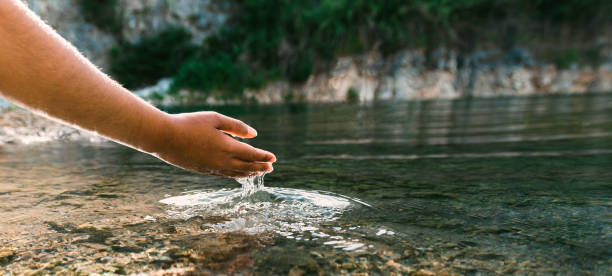 istock hand touches water in pond with sunshine 1404120097