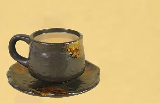 Brown ceramic coffee cup on a light brown background