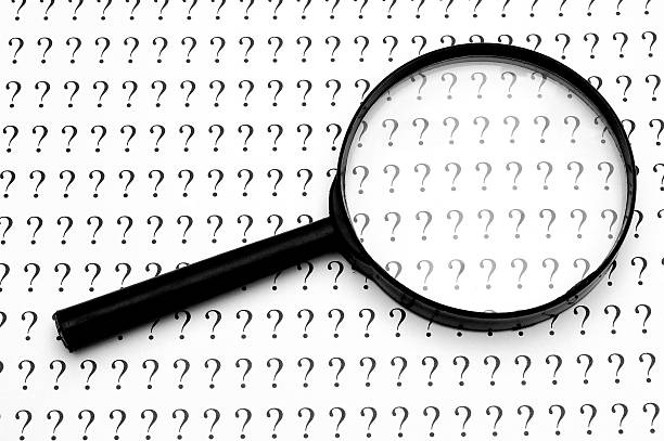 Magnifying glass and question marks stock photo