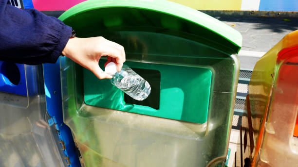 une femme jette des bouteilles d’eau dans une poubelle - packaging recycling bottle plastic photos et images de collection