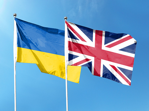 Ukrainian and British flags with blue sky. waving blue sky