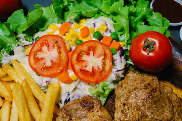 Steak salad with beef and vegetables on plate isolated on white background top view