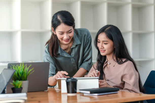 Two young Asian businesswoman is happy working on presentations using papers and tablet placed at the office. stock photo